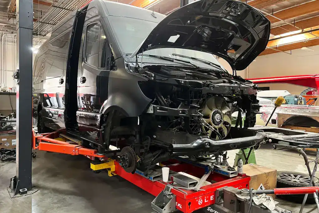 Commercial fleet van undergoing front-end collision repair in an auto body shop