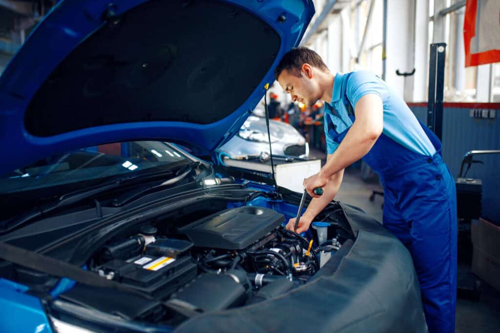 Technician inspecting a vehicle engine in a professional fleet maintenance garage
